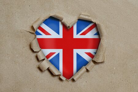 Heart shaped hole torn through paper, showing British flagの写真素材