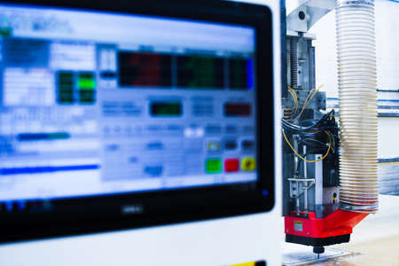 High speed plastic CNC machine pictured with the computer screen in foreground while cutting out a...