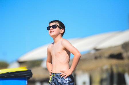 Happy young boy wearing sunglasses enjoys his time at the beachの写真素材