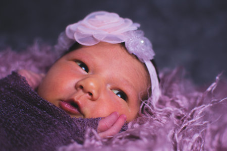 Portrait of a newborn girl in a purple violet setup background with copy space.の写真素材