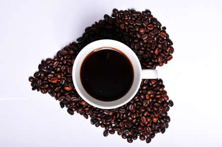Heart shaped coffee beans with a cup of coffee in the centre of it suitable for adverts, postcards,...