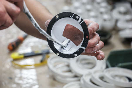 A worker is applying glue on the inside of the rear part of a punkah louvre in order to stick fluff...