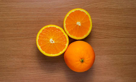 Orange, half of orange, orange lobule and basket with oranges on the wooden table