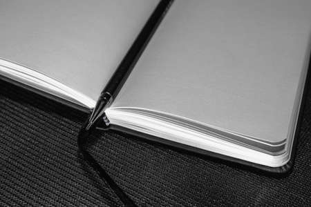 Photo of opened blank square book on black paper background.の写真素材