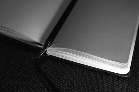 Photo of opened blank square book on black paper background.の写真素材