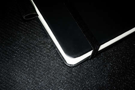 Notebook with black cover on black backgroundの写真素材