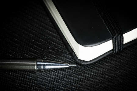Notebook with black cover on black backgroundの写真素材