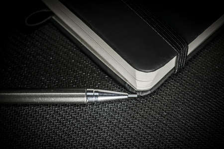 Notebook with black cover on black backgroundの写真素材
