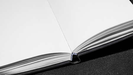 Photo of opened blank square book on black paper background.