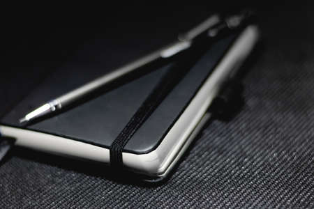 Notebook with black cover on black backgroundの写真素材