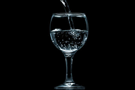 Pour water into glass on black background.の写真素材