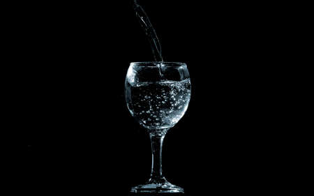 Pour water into glass on black background.の写真素材