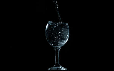Pour water into glass on black background.の写真素材