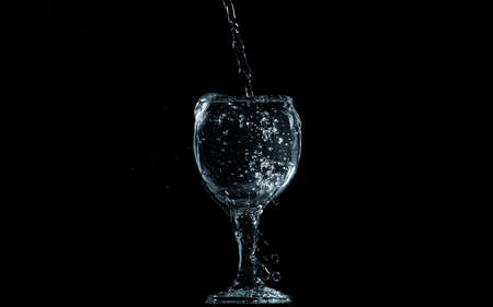 Pour water into glass on black background.の写真素材