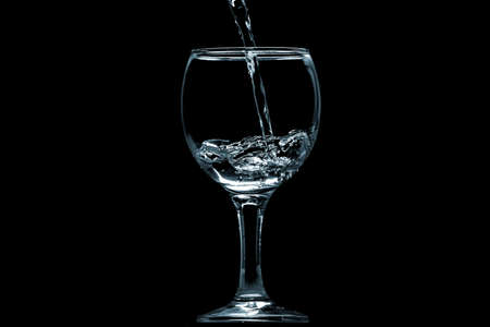 Pour water into glass on black background.の写真素材
