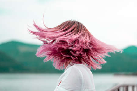 Woman with pink hair standing on the mountain top over blue sea view, photo tonedの写真素材