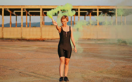 happy young woman having fun with colorful powder cloud. girl running with yellow color smoke bombの写真素材