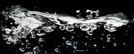 Clear water surface on a black with ripple and bubblesの写真素材