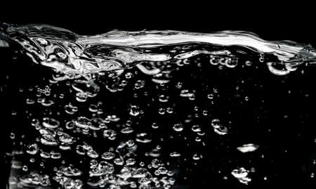 Clear water surface on a black with ripple and bubblesの写真素材