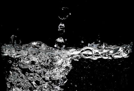 Clear water surface on a black with ripple and bubblesの写真素材