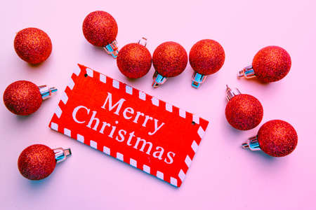 banner on pink background surrounded by red balloons on which writes merry christmasの写真素材