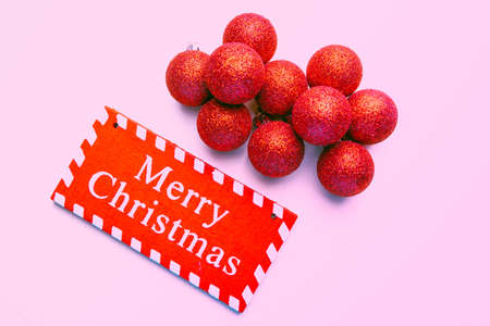 banner on pink background surrounded by red balloons on which writes merry christmasの写真素材