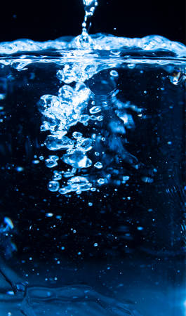 Pour water into glass on black background.の写真素材