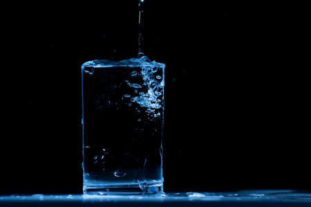 Pour water into glass on black background.の写真素材
