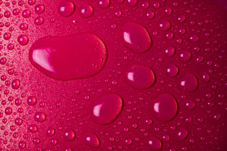 Drops of water on a red glass texture backgroundの写真素材