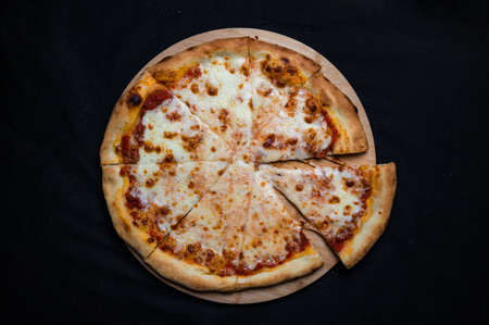 Pizza with tomato sauce and mozzarella cheese on a black background.の写真素材