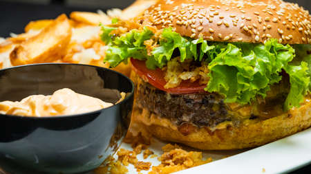 Burger with beef, french fries and sauce on a gray plateの写真素材