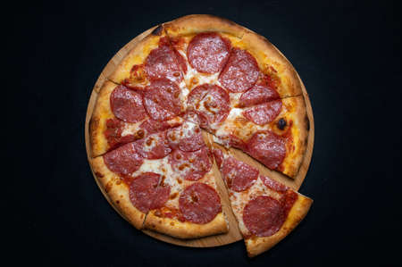 Pizza with tomato sauce, mozzarella and salami on a black background.の写真素材