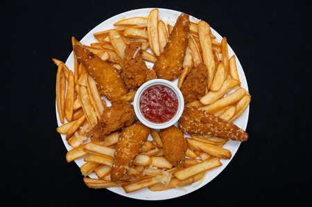 Crispy menu with spicy wings, french fries and chili sauce on a black background.の写真素材