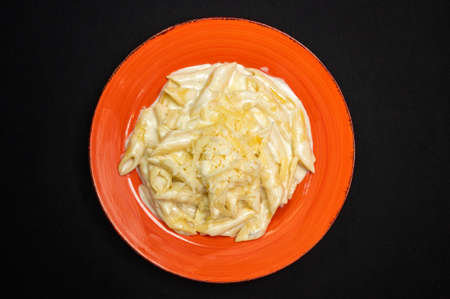 Carbonara pasta in red plate on a black background.