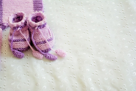 Baby violet knitted booties on white background