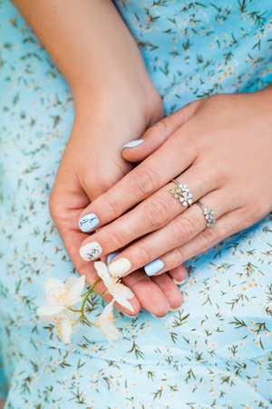 Female hands with flower on floral blue backgroundの写真素材