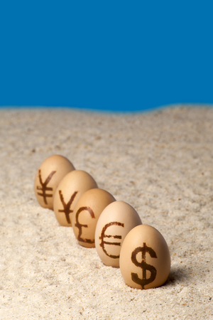 Universal money icon painted on eggs on the sandの写真素材
