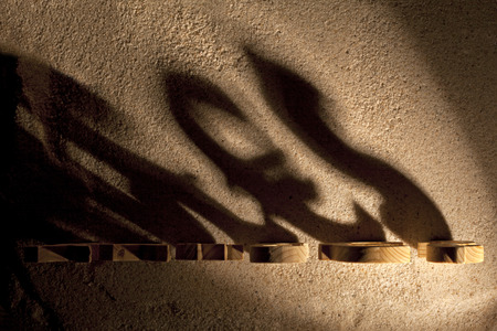 Wooden economy and currency unit's shadow on sandの写真素材