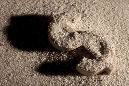 Wooden economy and currency unit in sand with shodow
