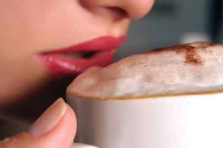 Woman is drinking her cappucino coffeeの写真素材