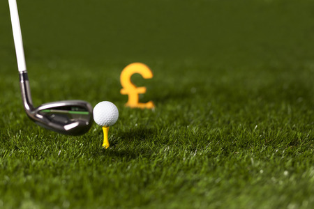 Targeting money with golf club and ball on green grassの写真素材