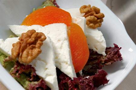 white cheese, dried apricot, walnut and green salad in a dishの写真素材