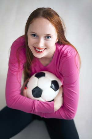 Beautiful long haired girl holding a soccer ball and smilingの写真素材