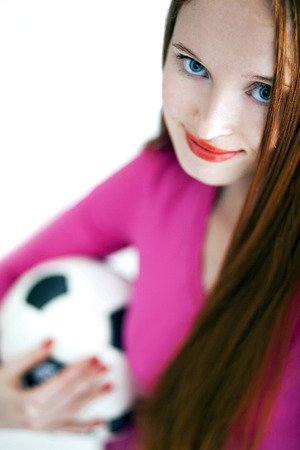 Beautiful red headed girl holding a soccer ball and smilingの写真素材