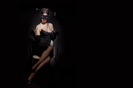 Beautiful and mysterious masked young woman on black backgroundの写真素材