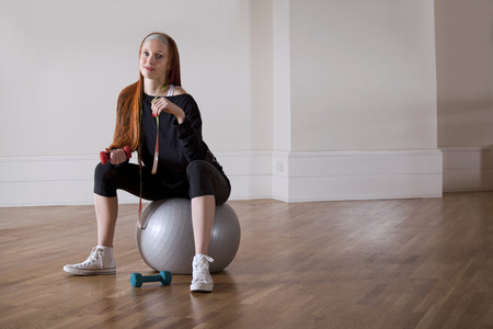 Woman is sitting with fitness ball, weights and measureの写真素材