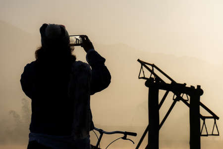 Silhouette of women take a photo wood ferris wheel at sunriseの写真素材