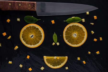 top view of piece orange and knife on slate stone. face smile happy. fresh fruit  conceptの写真素材