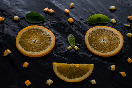 piece orange and knife on slate stone. face smile happy. fresh fruit  conceptの写真素材