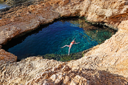 Young woman swim in the natural swimming pool Pissina of Koufonissi island, Greeceの写真素材